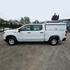 Side view of a white Chevrolet Silverado crew cab pickup truck with a white utility bed cap