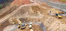 Excavators assisting construction crews on-site, with safety barriers in place to control access and protect workers.